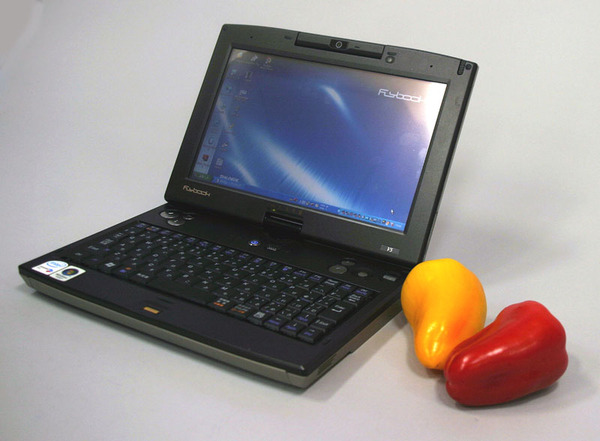 「FlyBook V5」。サイズ比較のため長さ約11cmのパプリカ（右）を置いてみた。なんでパプリカかといえば、ヨーロピアンだから……（産地は沖縄県）