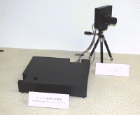 試作機では、撮影する部分(右)と画像処理を行なう部分(左の黒い箱)が分離しているが、実際にはシステムLSI『M32R/D』をデジタルカメラ本体に搭載できる