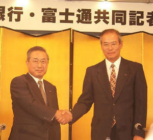 握手を交わすさくら銀行の頭取である岡田明重氏(左)と、富士通の社長である秋草直之氏