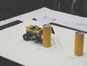 空き缶をアームで倒していくロボット。テーブルのエッジはセンサーで検知して戻っていく仕組み  