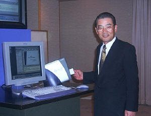 アプライアンスの前で、スマートカードを手にポーズをとる菅原社長