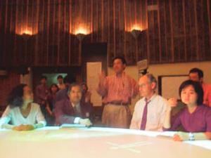 “ビジョンプラス7”の中日に行なわれた記者会見。画面中央は実行委員長の多摩美大の須永剛司教授  