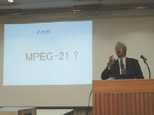 安田浩教授。スクリーンには“MPEG-21”という文字が投影されている