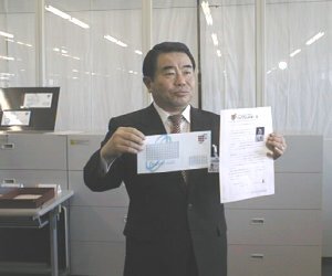 新東京郵便局長の佐藤暢男氏。手にするのは、郵政大臣から送られた第1号の“ハイブリッドメール” 