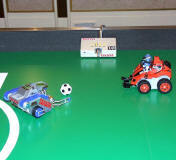 卓球台サイズの競技用フィールド(写真左)と、試作機による競技デモ(写真右)