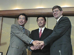 左より、がっちりと握手を交わす成毛氏と阿多氏、米本社アジア地区担当バイスプレジデントのピーター・クノック氏 