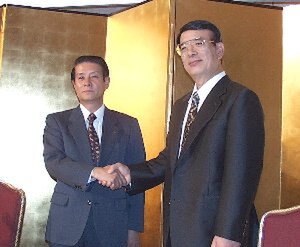 発表会場で握手を交わす松下の樋野取締役(左)とオラクルの佐野社長(右)