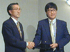 販売契約を結び握手する新日エレクトロニクス副社長の鈴木進氏(左)と、Trek 2000 International社CEOのヘンリー・タン氏 