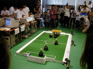 決勝戦の様子。近畿大学と大阪大学・明石高専の合同チームとの間で競われた。手前の円錐状のボディが合同チーム。ロボットが色つきのピンポン玉を付けているのは頭上カメラによる識別のため 