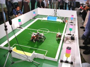 4脚リーグでは競技用AIBOを使った対戦デモが実施された。画面奥にボールを追うAIBOが見える 
