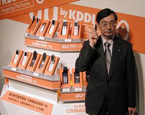 CDMA2000 1x対応携帯電話を持つ、KDDI代表取締役社長の小野寺正氏