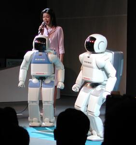 ホンダブースのステージイベントの様子。女性と青ASIMOが案内役を務め、ASIMOに関する最新ニュースを紹介