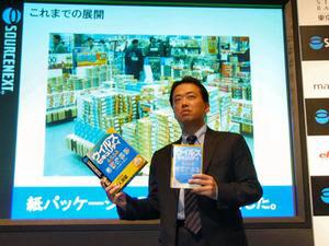 大きな紙パッケージの製品とスリムパッケージの製品を手に、スリムパッケージ化の取り組みについて語るソースネクスト代表取締役社長の松田憲幸氏