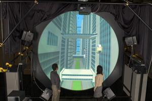 “ドーム型シームレスマルチプロジェクタ映像表示システム”のデモの様子。半球型のスクリーンの周囲に、プロジェクターが設置されている