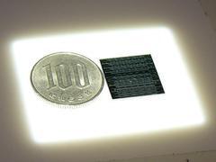シリコンレーザーのダイと100円玉を並べて。ダイ上でS字を描いているのがラマンレーザーの回路