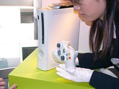 女性が手に持った様子。米国で現行Xboxが登場したときには、付属コントローラーの巨大さが問題とされたが、Xbox 360は適度なサイズになっている