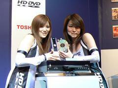 世界初の製品化となるHD DVDプレーヤー『HD-XA1』。左の女性が手にするのが付属リモコン。右はHD DVD-ROMのディスク