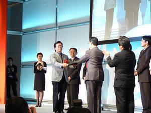 見事グッドデザイン大賞を受賞し、表彰を受ける三菱自 常務取締役の相川哲郎氏(左から3人目)とプロジェクトのスタッフ