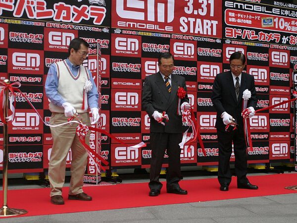 ヨドバシカメラ マルチメディアAkiba 取締役店長の松井昭二郎氏(左)、イー・モバイル 代表取締役会長兼CEOの千本倖生氏(中央)、ヨドバシカメラ 代表取締役社長の藤沢昭和氏(右)の3名がテープカットを行なった