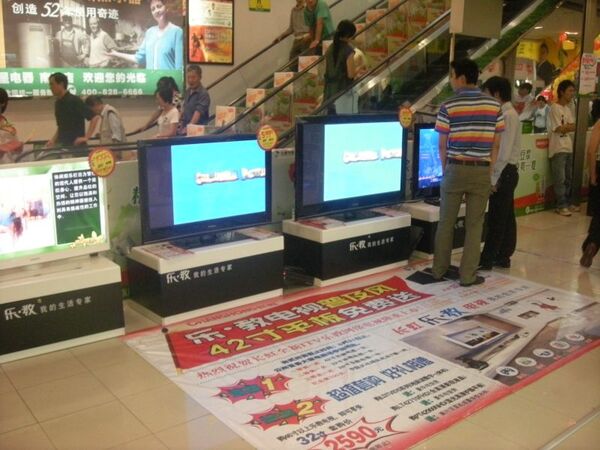 店舗前のエスカレーターで、中国メーカーがテレビの激安キャンペーンをアピール