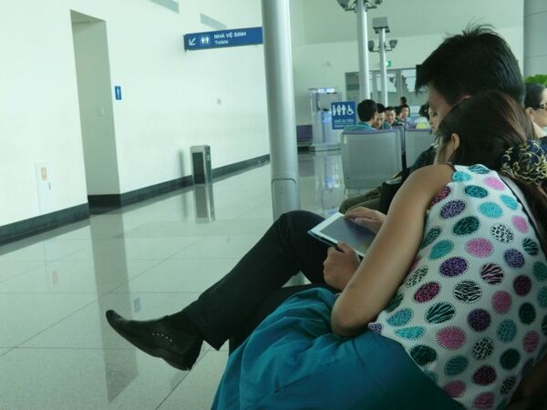 ベトナムの空港にて、タブレットで遊ぶカップル