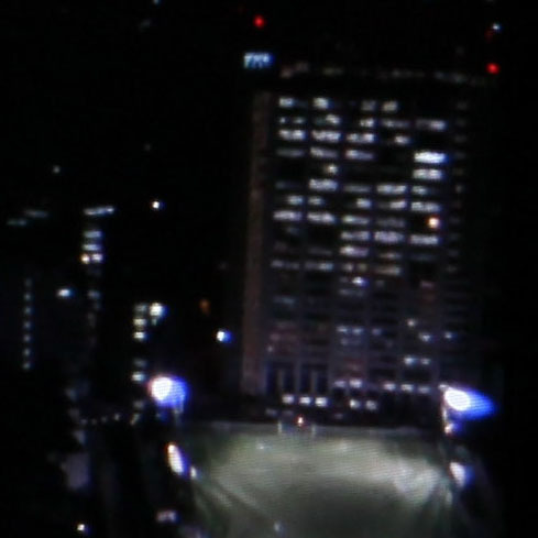 パナソニックのドキュメント番組の空撮シーン。明かりの灯ったビルの窓の奥の様子まで比較的鮮明に再現される。緑のスタジアムを照らすライトとビルの蛍光灯の色の違いもよく出る
