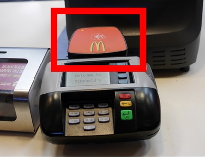 マクドナルドのレジ横に置かれたクレジットカードリーダー。奥の赤い部分に非接触決済マークが表記されている