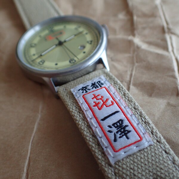 昔の一澤帆布製の腕時計バンドのように今は「喜一澤」タグが縫い付けられている。バンドにも文字盤にも同じ　京都「喜一澤」のロゴが重複してあり、同時に見る確率がほぼ100％なのでちょっとダサい