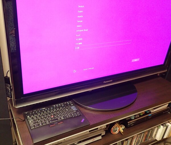 最初の設定は言語選択だ。自宅のテレビの横にHDMI延長ケーブルにぶら下がったIntel Compute Stickが見える。設定画面の色は何とかしてほしいなぁ……