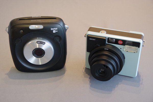 SQ 10は印刷結果を上面に排出するが、チェキ「instax mini90 ネオクラシック」を90度回転して転用した「Leica　SOFORT」（右）は、向かって右側の側面にフィルムを排出する