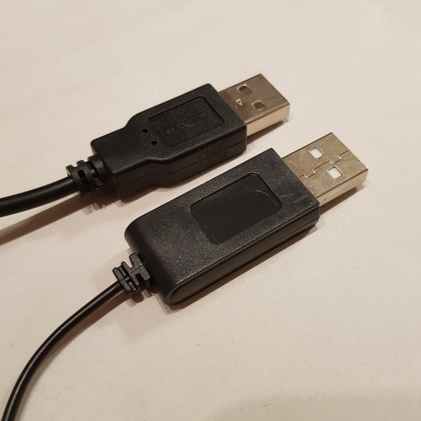 充電状況を示すLEDライトの封入された特殊な専用USBプラグ（手前）と一般的なUSBプラグのType-A（奥）