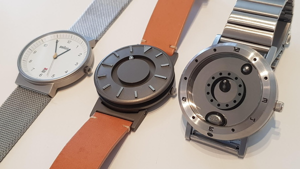 一般的な見慣れた腕時計（左端）と時針、分針のイメージと位置が違うと感じるマグネットで動作する持球、分球を採用した腕時計（中央：ブラッドレイ・ウォッチ、右：液体金属ウォッチ）