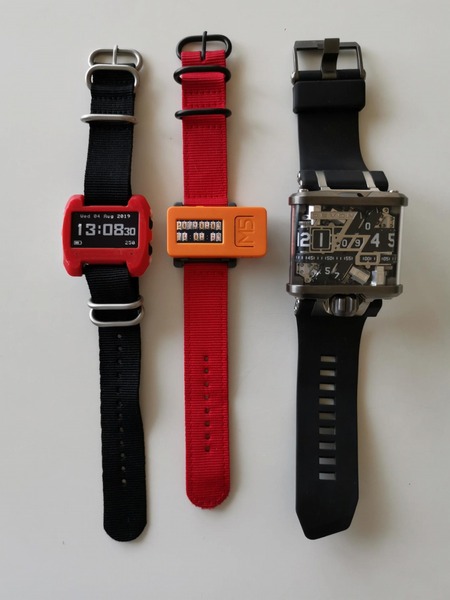 最近の筆者愛用のなんちゃって腕時計3本。左は今回のwatchX。中央は1950円で買った「M5StickC」に友人にアプリを入れてもらったなんちゃってMiniニキシー管腕時計。時刻設定を、起動時に筆者のスマホのテザリング機能を使ってNTPで自動設定するように改良してもらった。右端はこの7年で4年くらいは故障して米国で修理を受けてるダメな奴だが、見離せない超メカ腕時計「Devon」。すべて有難い他力創発で実現している。腕時計って、めんどうで手間のかかるモノほど楽しい変態世界だ