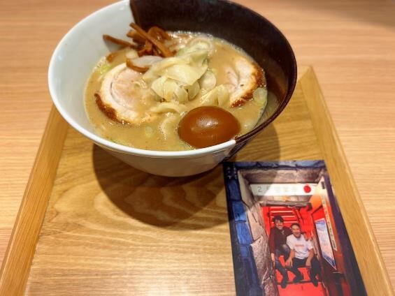 ラーメンには、いろんな思い出が詰まった凪の階段で肩を組む二人のポストカード付き