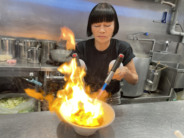 丼に注がれたスープをバーナーで炙る女将の姿に、お客様の目が釘付け!