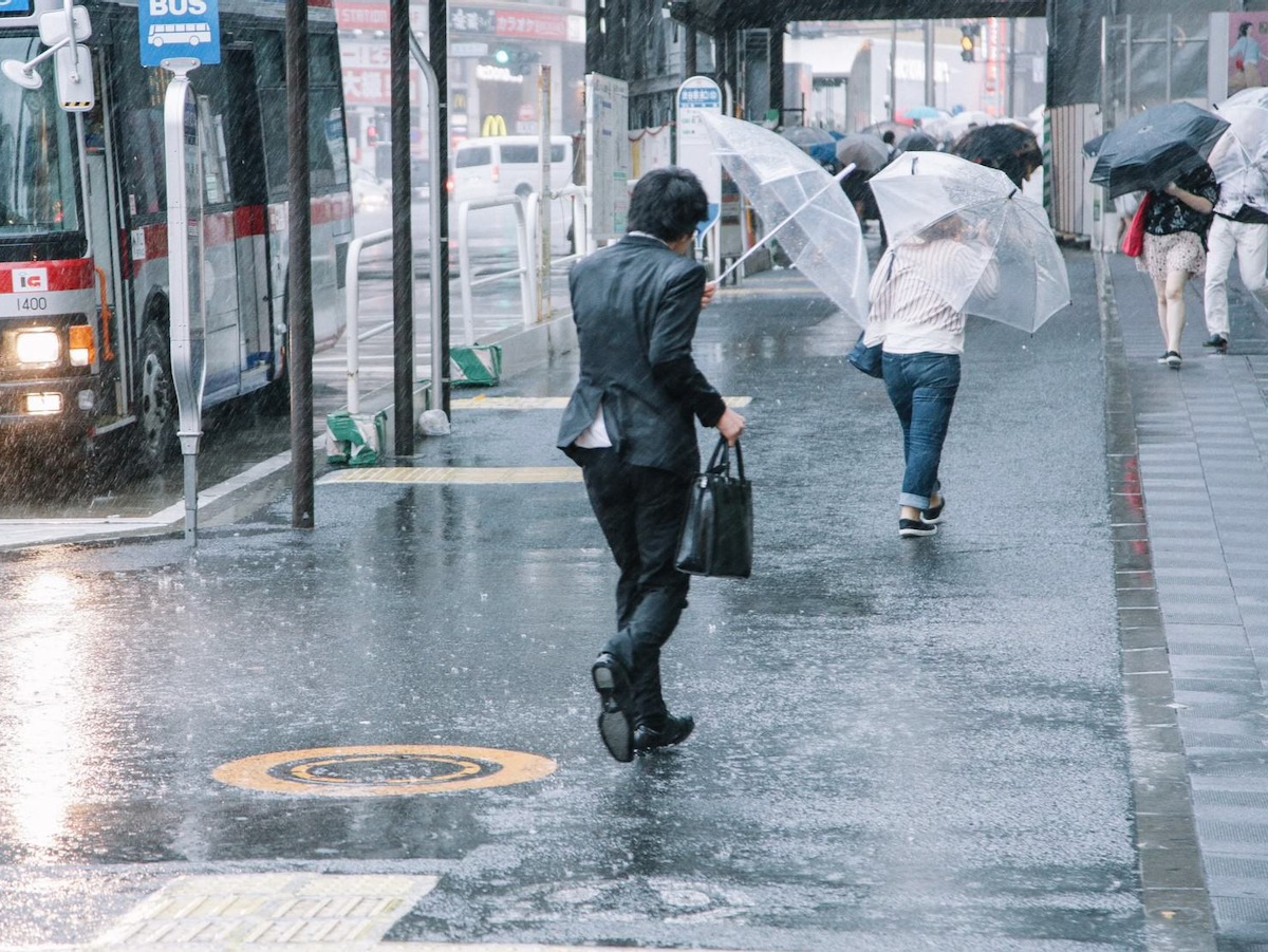 大雨と強風の中、出社する男性
