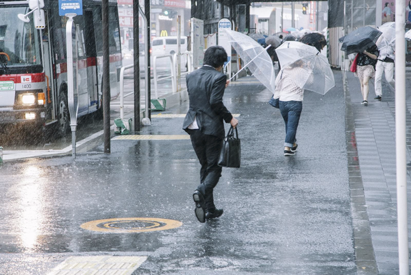 大雨に降られる通勤客の写真